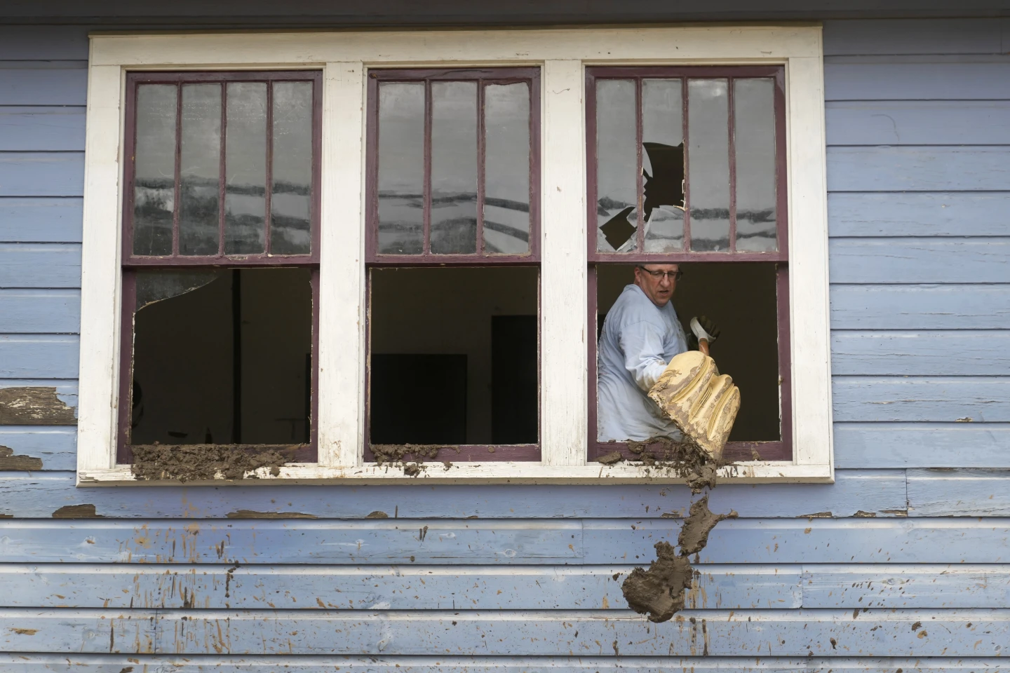 Ben Phillips scoops mud out a window of his house left in the wake of Hurricane Helene, Tuesday, 1 October 2024, in Marshall, N.C. Photo: Jeff Roberson / AP Photo