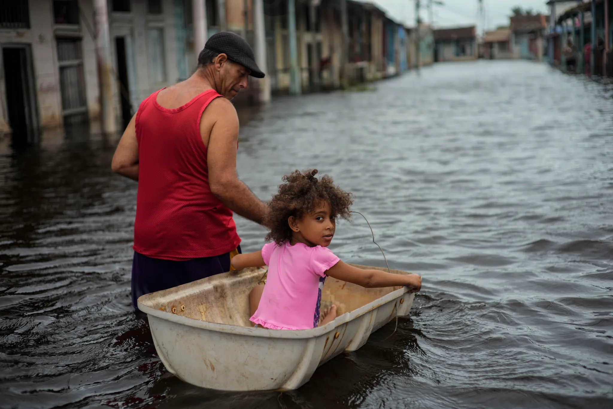 Jesus Hernandez guides his granddaughter Angelina via a container through a street flooded in the passing of Hurricane Helene, in Batabano, Mayabeque province, Cuba, on Thursday, 26 September 2024. Photo: Ramon Espinosa / AP Photo